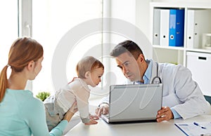 Woman with baby and doctor with laptop at clinic