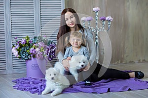 Woman and baby girl playing with whit hairy dog in studio shoot on a purple