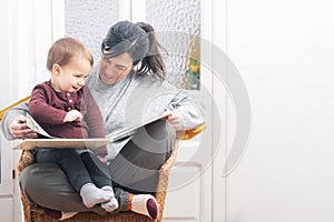 A woman and a baby are sitting together and reading a book