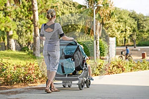 Woman with baby stroller walks in the park