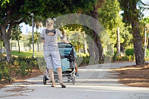 Woman with baby stroller walks in the park