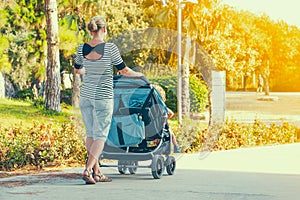 Woman with baby stroller walks in the park