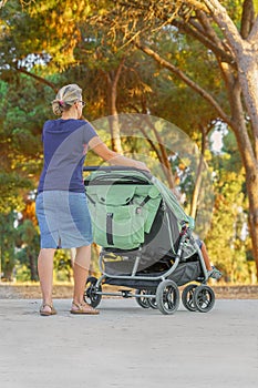 Woman with baby stroller walks in the park