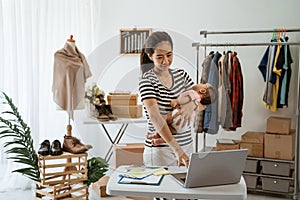Woman with baby working from home of her online ecommerce shop