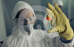 Woman with baceriological protective suit looking at an antidote vial photo