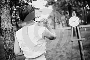 Woman back playing darts outside throws target