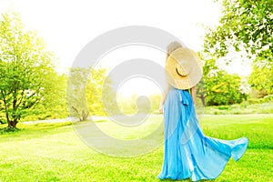 Una mujer trasero en naturaleza hermoso elegante en largo tiempo azul ropa un sombrero en el verano 