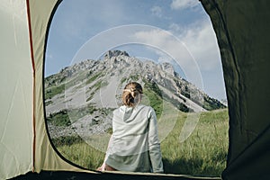 Woman back in tent with mountain view in Montenegro, camper enjoys the view