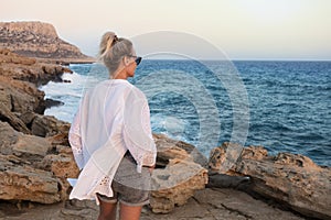 Woman on the background of the sea sunset. Enjoying life and looking at the sea.