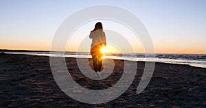 Woman on the background of the sunset the sun on the seashore does exercises