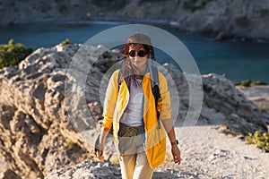 A woman with a backpack on the background of the sea. Portrait of a woman in tourist gear on the background of the sea.