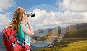 Woman with backpack and camera at big sur coast