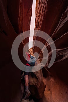 Woman with backpack climbing over large boulder inside Little Wi