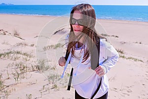 Woman with backpack climbs on sand dune and looks at sea from top on vacation.