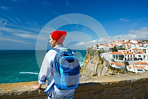 Woman with a backpack enjoys a view of the ocean coast near Azenhas do Mar, Portugal