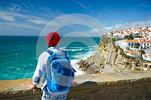Woman with a backpack enjoys a view of the ocean coast near Azenhas do Mar, Portugal