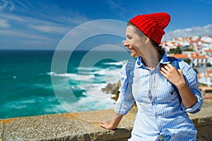 Woman with a backpack enjoys a view of the ocean coast near Azenhas do Mar, Portugal