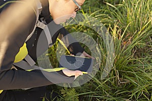 Woman with backpack geocaching with digital compass