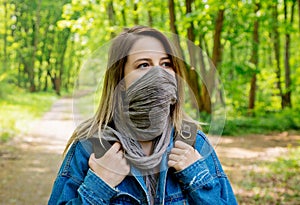 Woman with backpack hide face with a scarf in forest