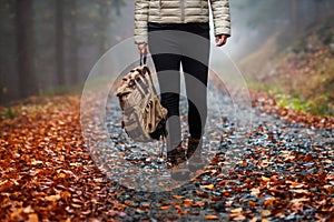 Woman with backpack and hiking boot walking on trail in autumn forest