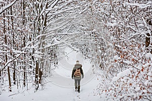 Woman with backpack is hiking in snowy woodland