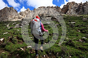 Woman with backpack hiking in sunrise mountains