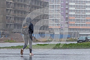 A woman with a backpack and a hood runs in the pouring rain
