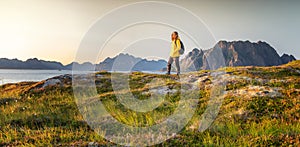 Woman with a backpack looks at the fjord. Ocean and mountain sunset landscape. Scenic view. Travel, adventure Explore North Norway