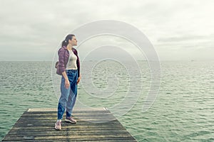 Woman with a backpack, looks at the sea, on a wooden pier. Freedom. Trips