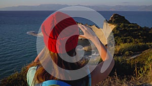 Woman with a backpack makes photo of the Cape Drastis at Corfu island in Greece