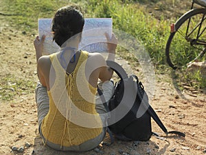 Woman With Backpack And Map Sitting In Dirtroad