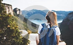 Woman with backpack meditating listen to music with headphones and looking view landscape river and peak mountain, female tourist