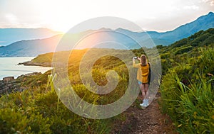 Woman with backpack photographs the mountains