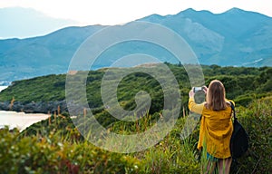 Woman with backpack photographs the mountains