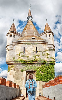 Woman with backpack posing on bridge in front of Vajdahunyad castle in Budapest, Hungary