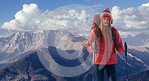 A woman with a backpack rest on top of the mountain and enjoy the views of the valley