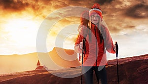 A woman with a backpack rest on top of the mountain and enjoy the views of the valley