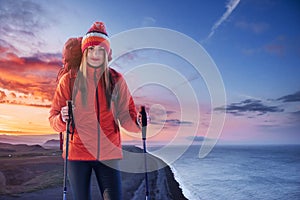 A woman with a backpack rest on top of the mountain and enjoy the views of the valley