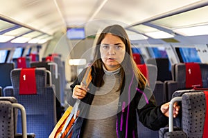 Woman with backpack on shoulder standing in aisle between seats in train