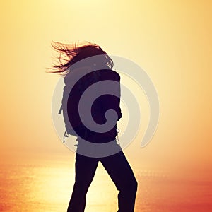 Woman with backpack standing on sunrise windy coast