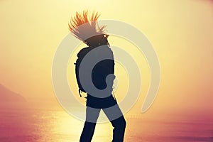 Woman with backpack standing on windy coast