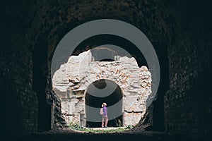 Woman with backpack stands among the ruins of ancient building