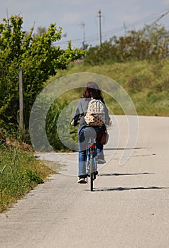 woman with a backpack on their shoulders pedaling leisurely on the cycle path in the countryside photo