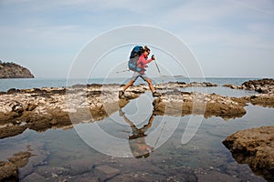 Woman with backpack treks on a sea coast