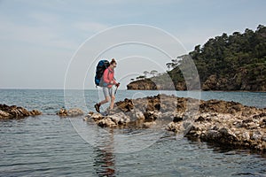 Woman with backpack treks on sea shore