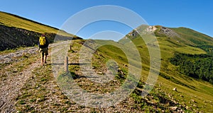 Woman with backpack walking along a path in the Caucasus mountains