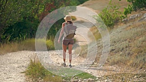 Woman with backpack walking away alone at road in mountains. Travel lifestyle concept adventure outdoor summer vacations