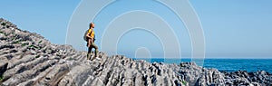 Woman with backpack walking through flysch rock landscape