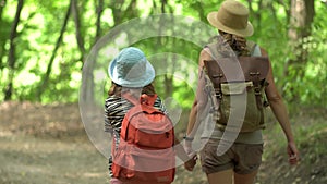Woman with backpack walking with girl at road in forest. Travel lifestyle concept adventure outdoor summer vacations