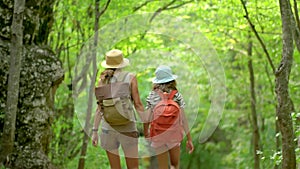 Woman with backpack walking with girl at road in mountains. Travel lifestyle concept adventure outdoor summer vacations